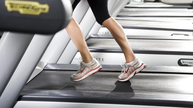 Nahaufnahme von Beinen in Sporthose, die auf einem Laufband joggen, mit modernen Laufschuhen.