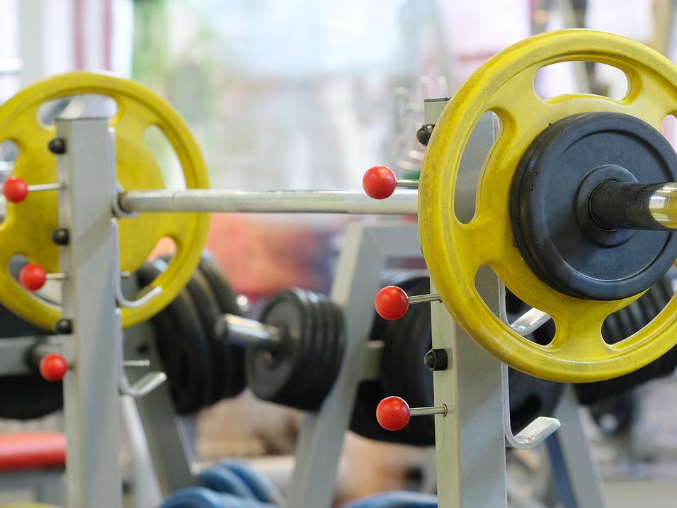 Nahaufnahme einer Langhantel mit gelben und schwarzen Gewichten in einem Fitnessstudio.