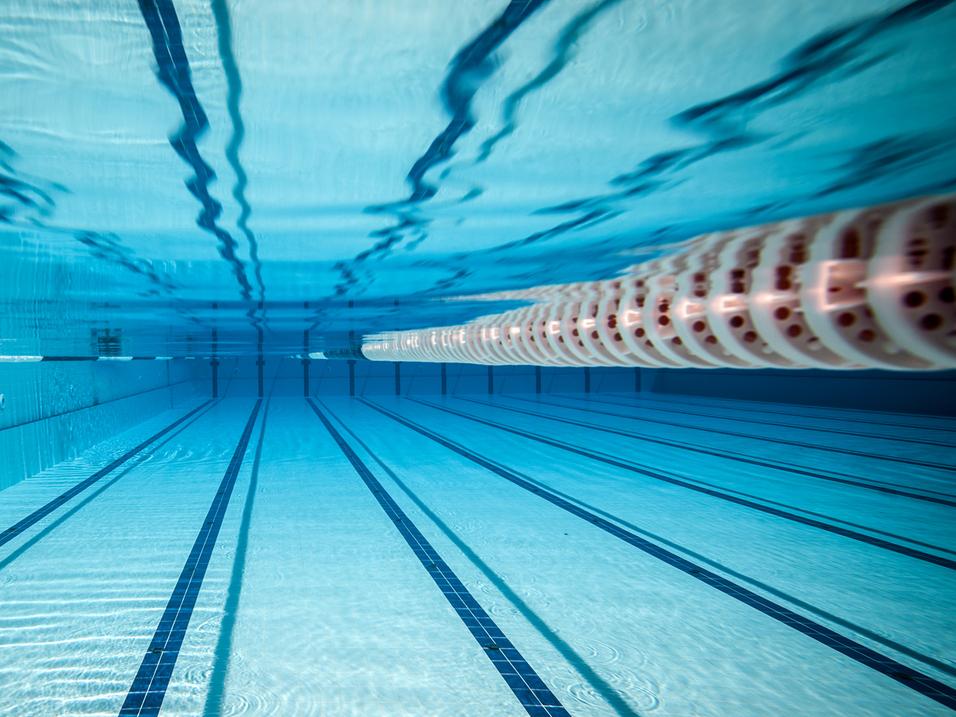 Unterwasseransicht eines Schwimmbeckens mit klaren, blauen Wasser und markierten Bahnen.